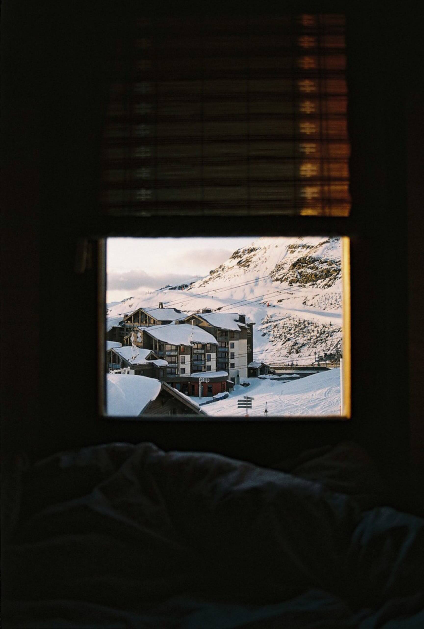 snow covered building viewed through open window